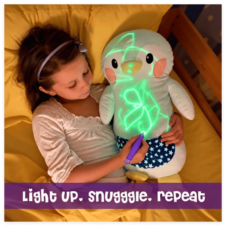 Child drawing a glowing picture on a penguin plush while relaxing in bed