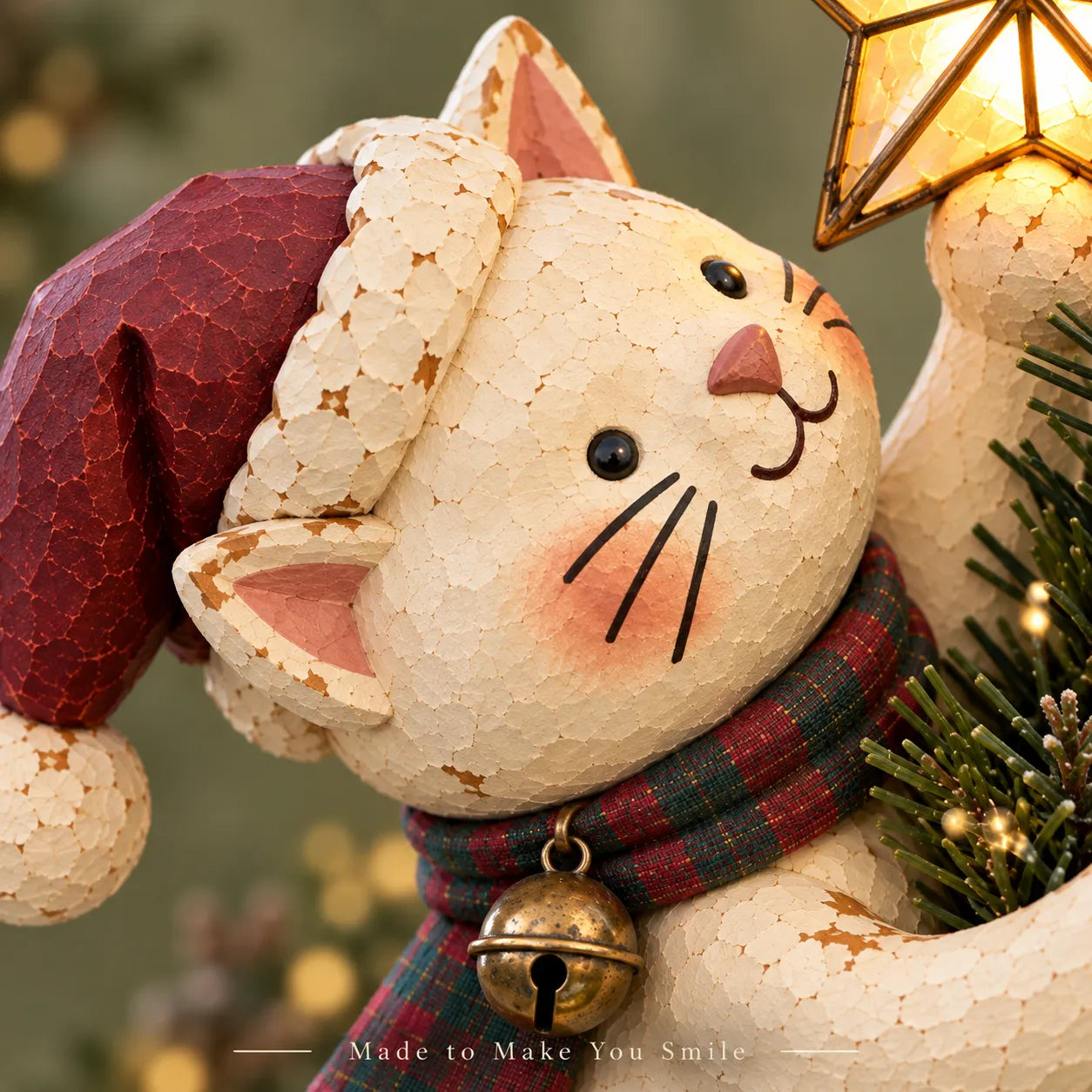 Cream-colored Christmas cat wearing a Santa hat and plaid scarf, holding a glowing golden star at the top of a Christmas tree