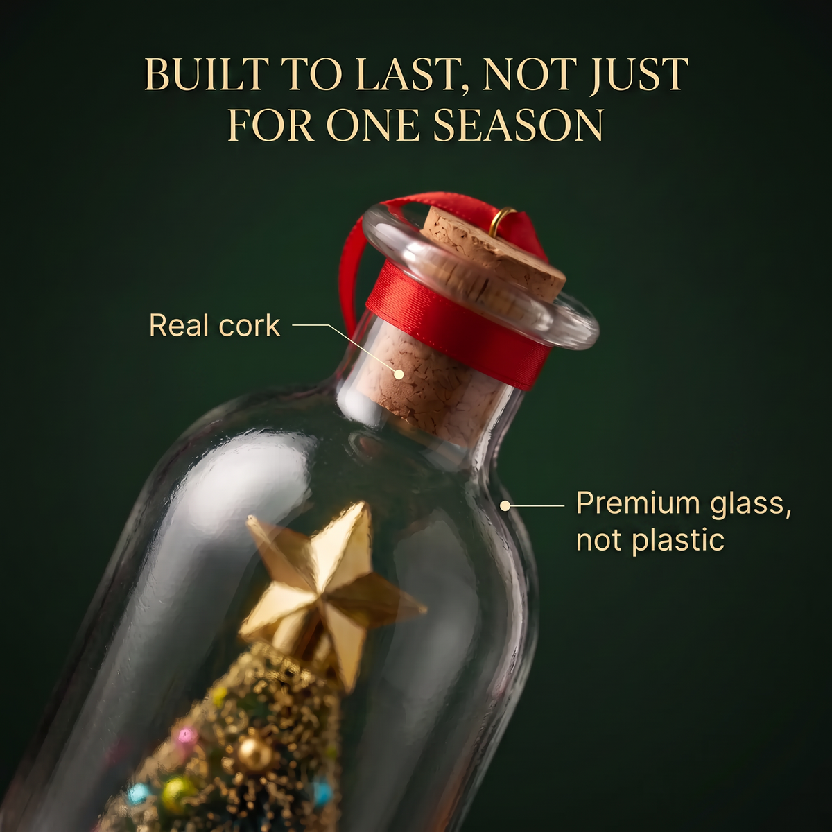 A clear glass bottle ornament with a cork stopper and red ribbon, shown against a dark green background with text reading 'BUILT TO LAST, NOT JUST FOR ONE SEASON,' 'Real cork,' and 'Premium glass, not plastic.' A small gold star and glittery tree decoration are visible inside.