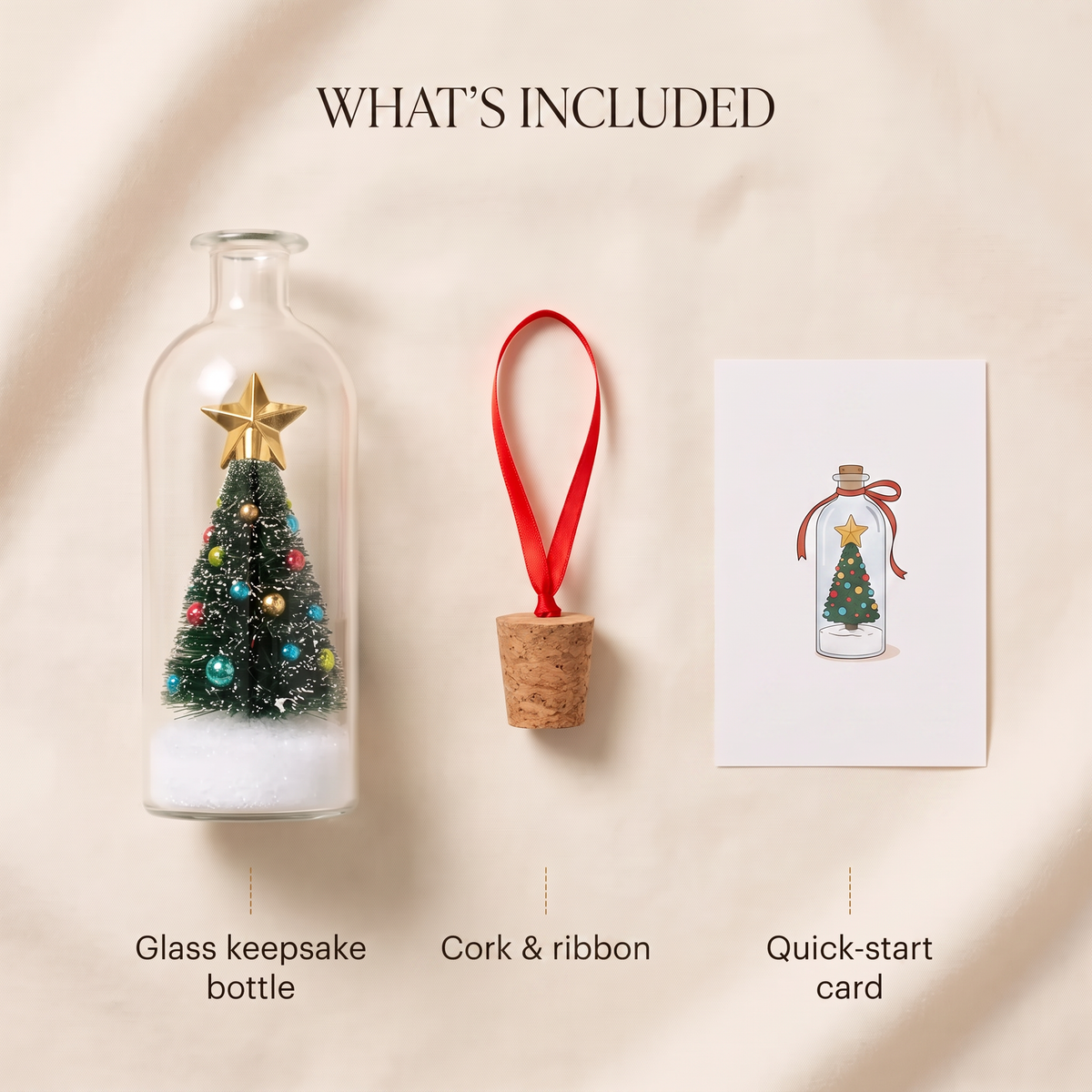 A product presentation showing a glass keepsake bottle with a miniature Christmas tree, a cork ornament with a red ribbon, and a quick-start card, all labeled under the heading 'WHAT'S INCLUDED' on a beige fabric background.
